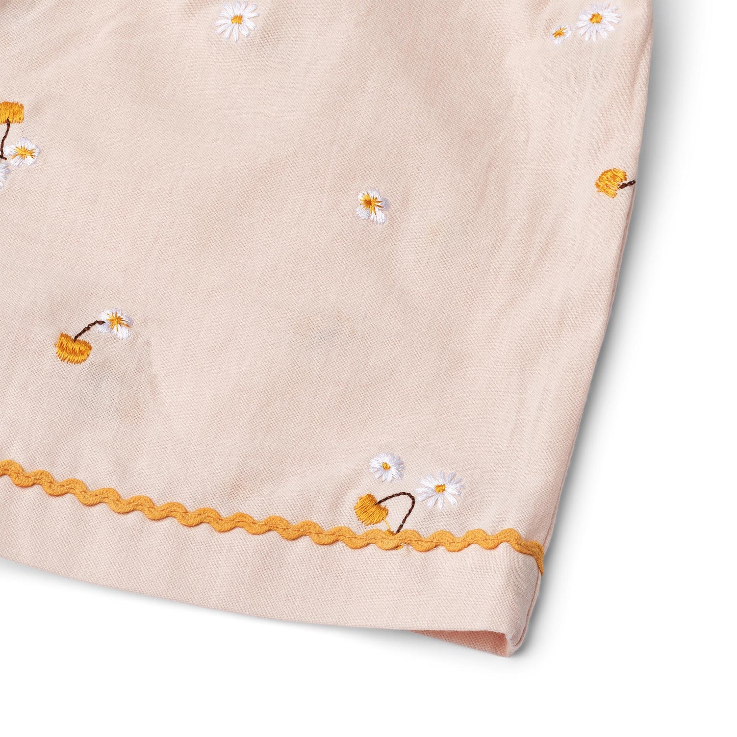 Close-up of delicate lace trim detail along the hem of the wheat-colored girls' shorts.