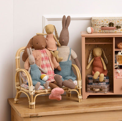 Children's toys including dolls and stuffed animals on a wooden shelf.