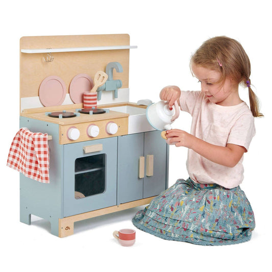 Child playing with a toy kitchen set on a white background