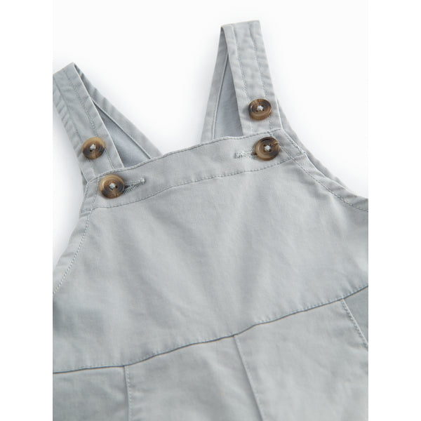 Light blue denim overalls with wooden buttons on a white background