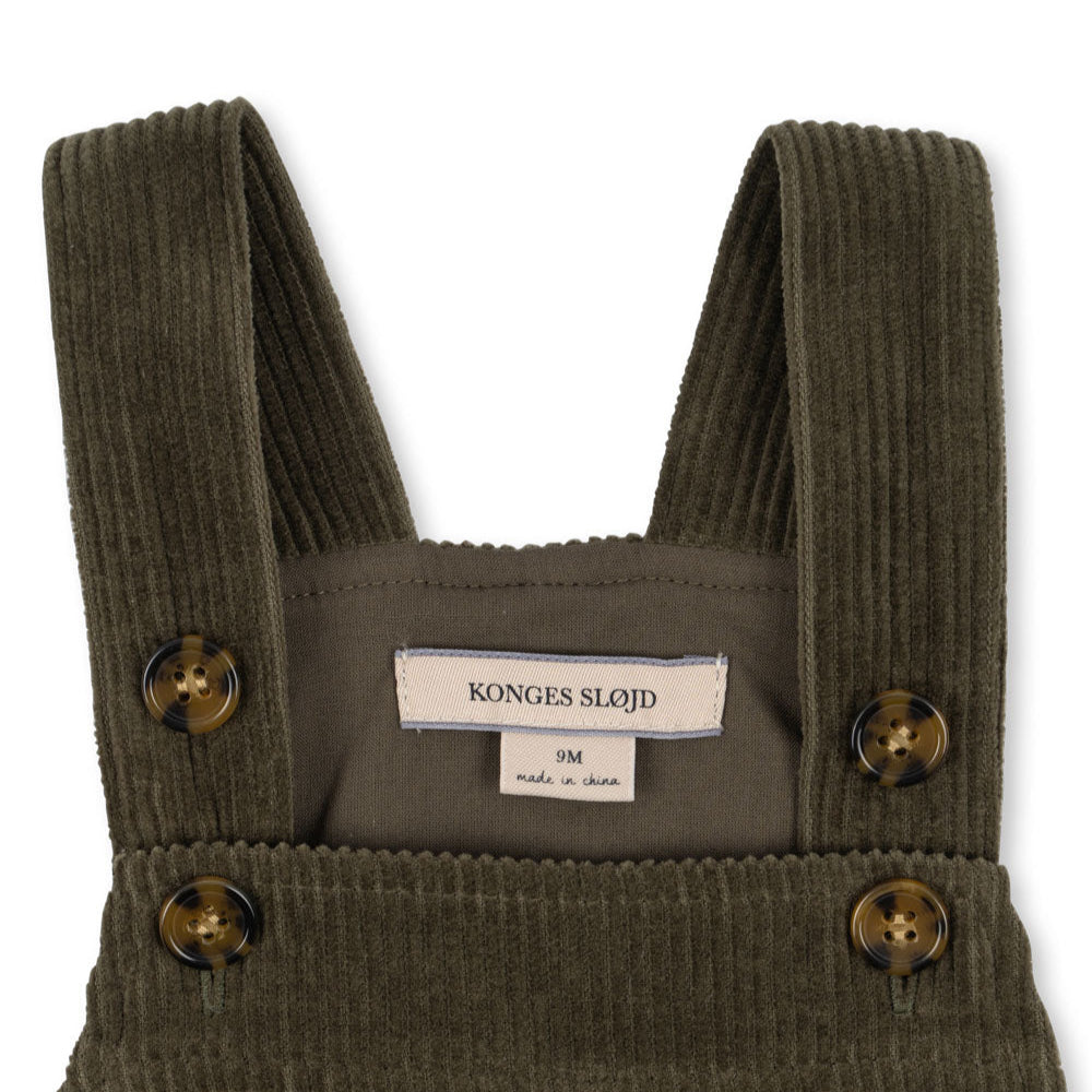Green corduroy overalls with button details on a white background