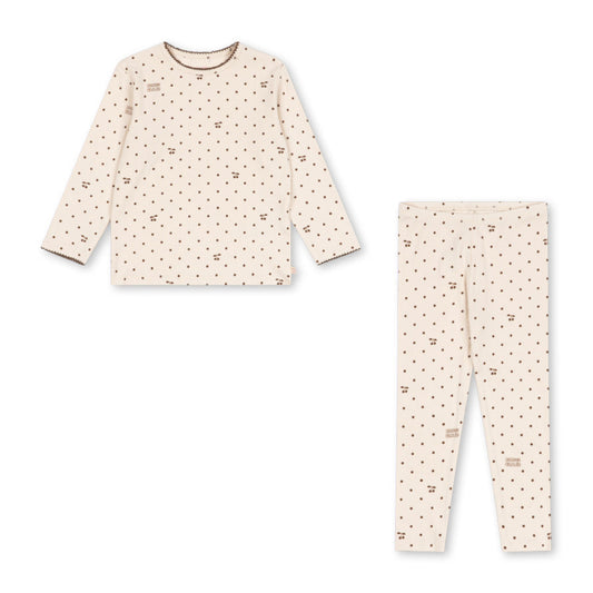 A two-piece children's pajama set featuring a long-sleeve top and matching pants in a warm cream color with a small brown dalmatian-style dog print, laid out on a solid white background.