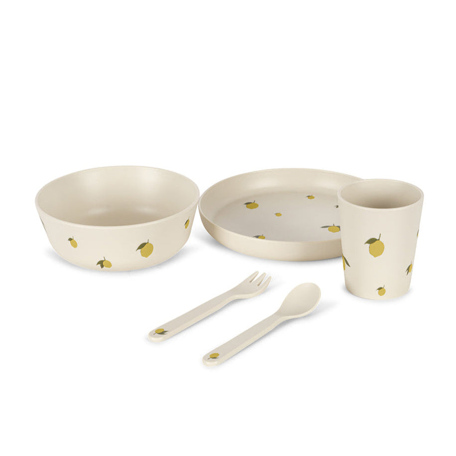 Set of children's tableware with bowls, plate, cup, fork, and spoon on a white background. Knoges Slojd