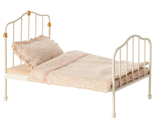 Small bed with white metal frame and pink bedding on a white background
