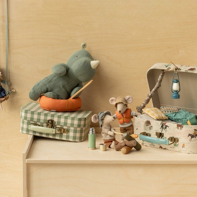 Toy elephant on a suitcase with other toys on a wooden shelf