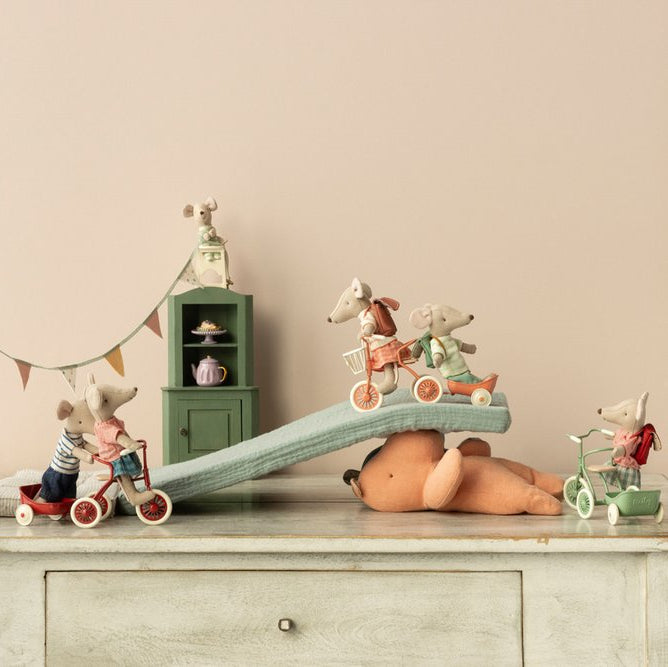 Toy mice with accessories on a wooden surface with a neutral background