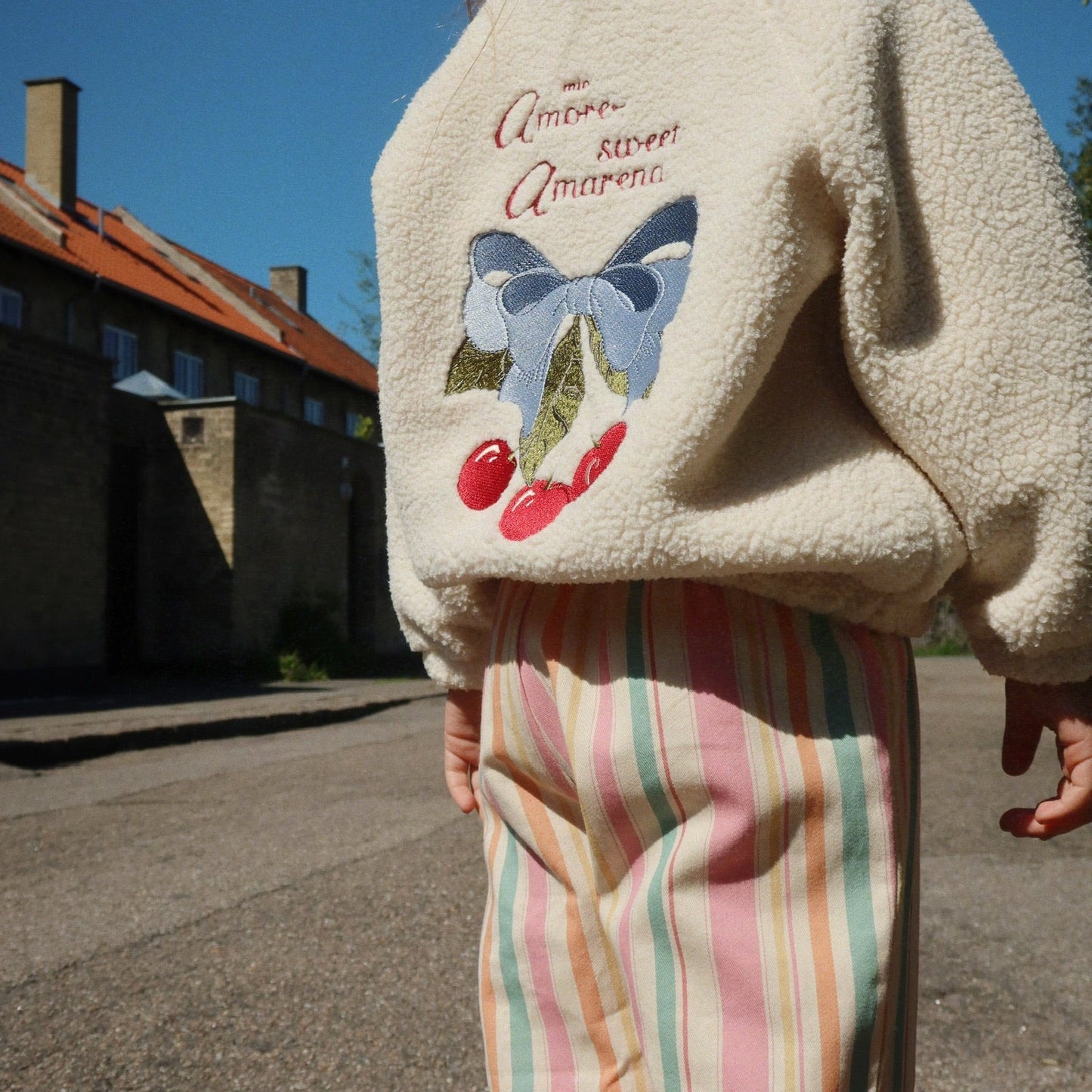 Girls wearing a cream-colored fleece jacket with a butterfly design outdoors.