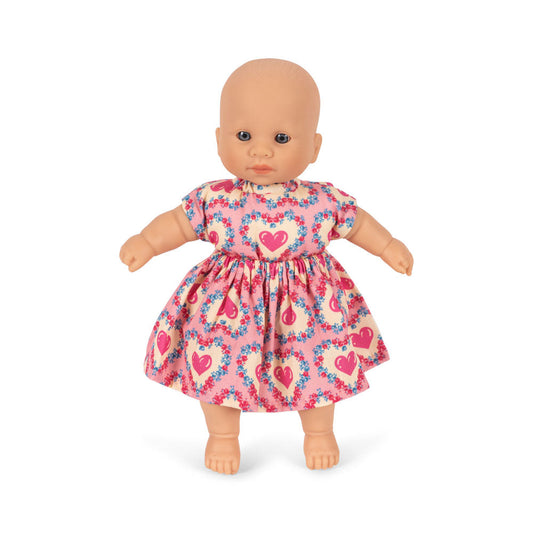 Doll wearing a pink dress with heart patterns on a white background