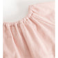 Close-up of a light pink corduroy garment, showing the textured fabric and gathered neckline on a white background.