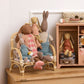 Children's toys including dolls and stuffed animals on a wooden shelf.