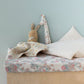 Children's bed with floral bedding, plush toys, and a light blue wall.