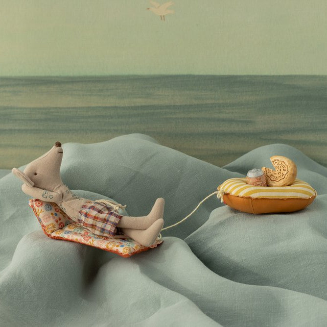 Illustration of a mouse lying on a cushion with a cookie in a desert landscape
