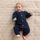 Baby wearing a navy blue outfit lying on a beige quilted blanket