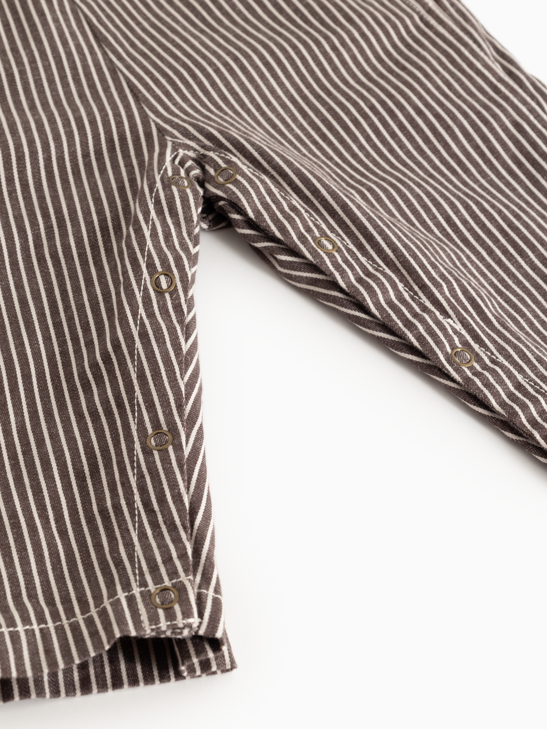 Close-up of a brown and white striped shirt with buttons on a white background