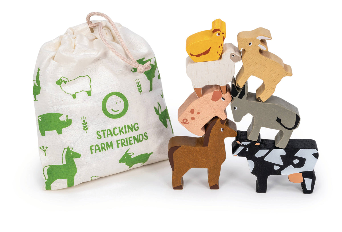 A children's stacking toy set featuring wooden farm animals and a matching fabric drawstring bag. The set includes a brown horse, black-and-white cow, gray donkey, pink pig, beige sheep, yellow chicken, tan goat, and a white goat, with the bag printed in green with the text 'STACKING FARM FRIENDS'.