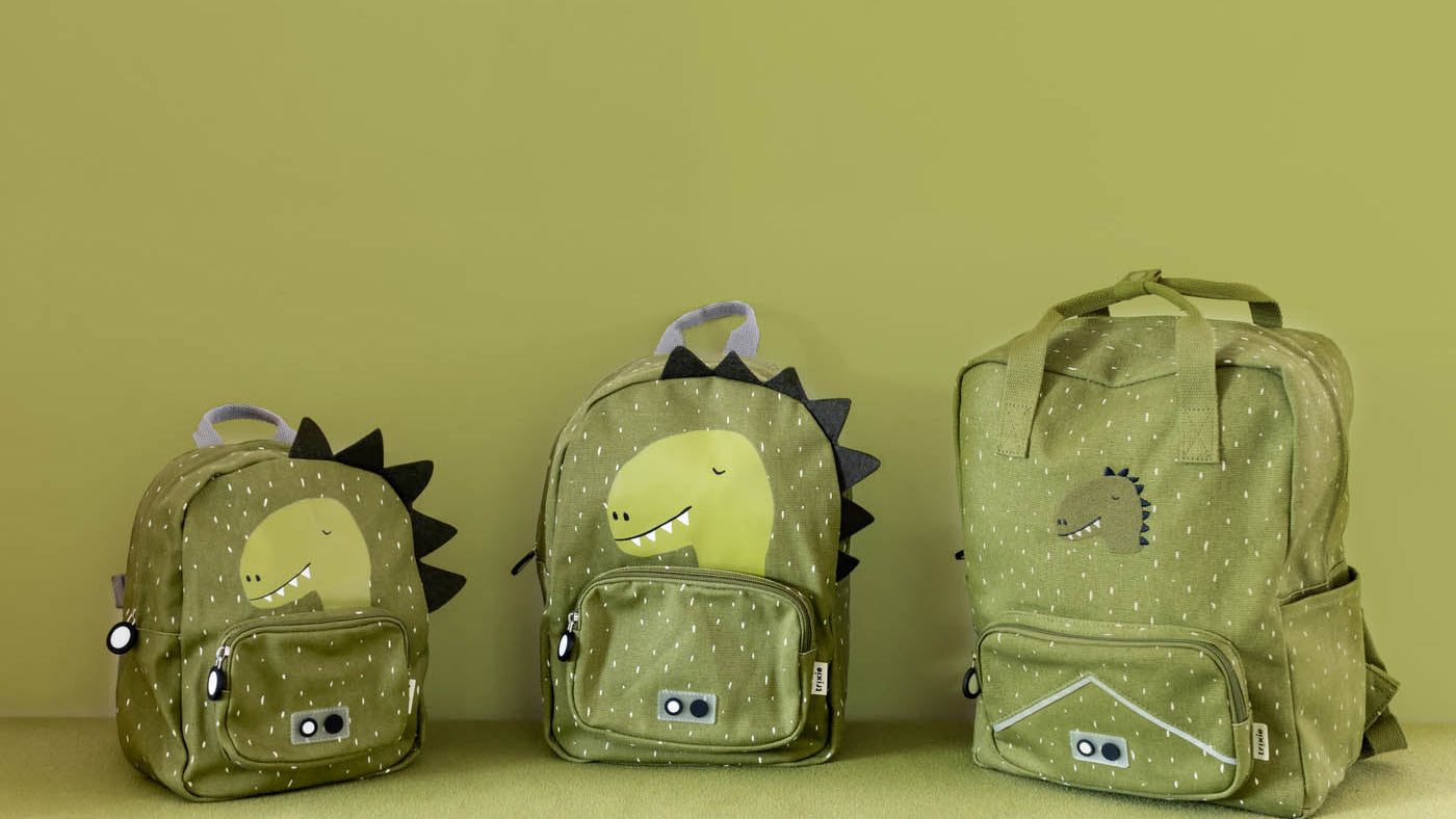 Three green backpacks with dinosaur designs on a matching background