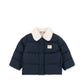 A navy blue puffer jacket with a cream-colored faux fur collar, featuring horizontal quilting and a small rectangular brand patch on the left chest, displayed against a solid white background.