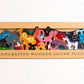 Box of handcrafted wooden jigsaw puzzles with animal designs on a white background
