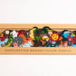 Box of handcrafted wooden jigsaw puzzles with colorful illustrations on a white background