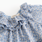 Close-up of a blue floral print garment with ruffled trim and a visible Mommy Jane brand label.