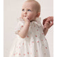 Baby in a floral dress with a plain background