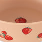 Beige bowl with red strawberry pattern on a beige background