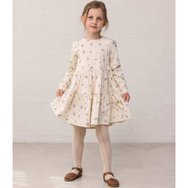 Young girl wearing a floral dress on a plain background