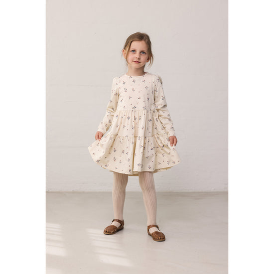 Young girl wearing a floral dress on a plain background