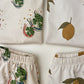 Children's clothing with lucky horseshoe, four-leaf clover, and lemon designs on a white background.