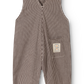 A baby romper with vertical brown and white stripes, featuring a front patch pocket with a small embroidered brand patch, shown against a plain white background.
