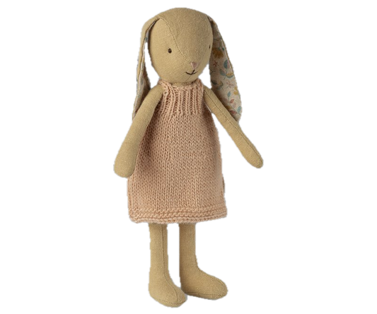 Knitted toy rabbit with a beige dress on a white background