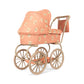 A vintage-style doll pram stroller with a peach-colored quilted fabric cover featuring a small teddy bear pattern, paired with a natural wood frame and four spoked wheels, shown on a plain white background.