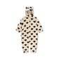 A cream-colored plush hooded one-piece jumpsuit covered in a black heart pattern, shown against a plain white background.