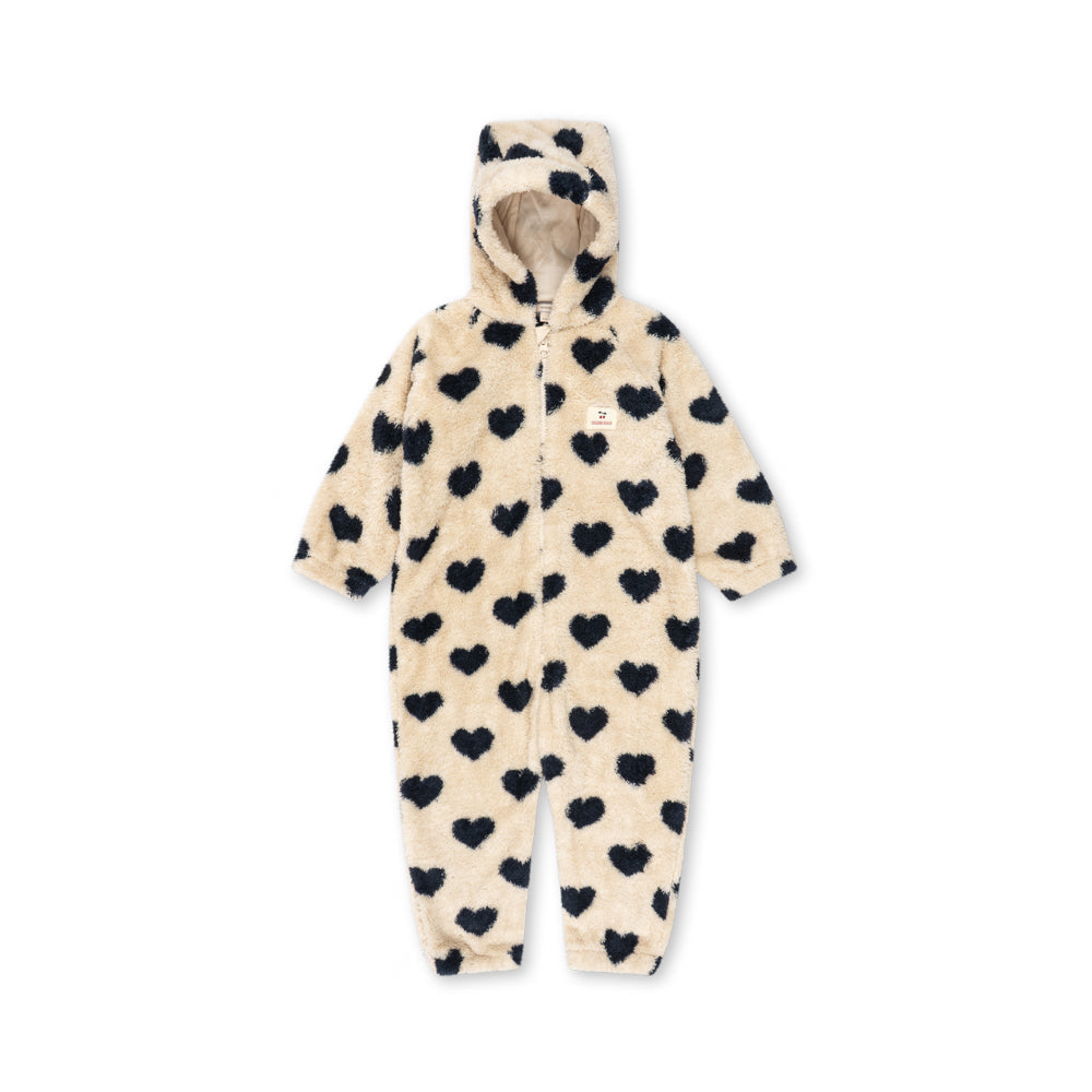 A cream-colored plush hooded one-piece jumpsuit covered in a black heart pattern, shown against a plain white background.