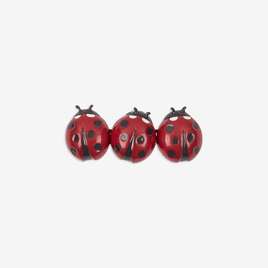 Three red ladybug-shaped earrings on a white background
