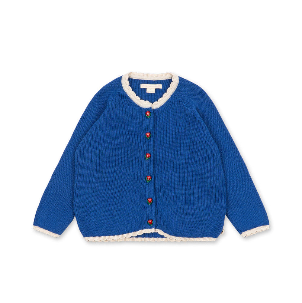 A royal blue knit cardigan sweater with white scalloped trim on the collar, cuffs, and hem, featuring decorative red and green buttons down the front, displayed on a clean white background.