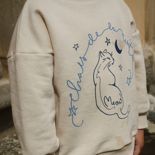 Person wearing a beige hoodie with a fox design and text outdoors.