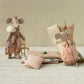 Two plush mouse toys with decorative clothing on a textured surface with a patterned wall background.