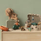 Collection of toys including a teddy bear, toy car, and playset on a wooden surface with a green wall background.