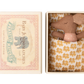 Small brown stuffed elephant toy in a decorative box with a floral pattern