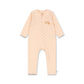 A baby long-sleeve footless one-piece jumpsuit in a pale peach-pink color with a small repeating orange pattern and a small 'the little bear' logo on the left chest, displayed flat against a white background.