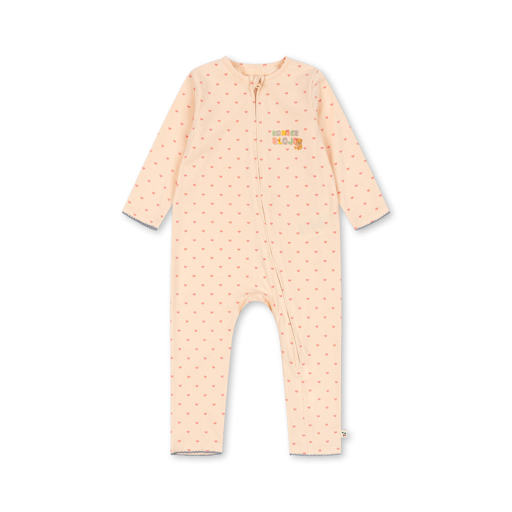 A baby long-sleeve footless one-piece jumpsuit in a pale peach-pink color with a small repeating orange pattern and a small 'the little bear' logo on the left chest, displayed flat against a white background.