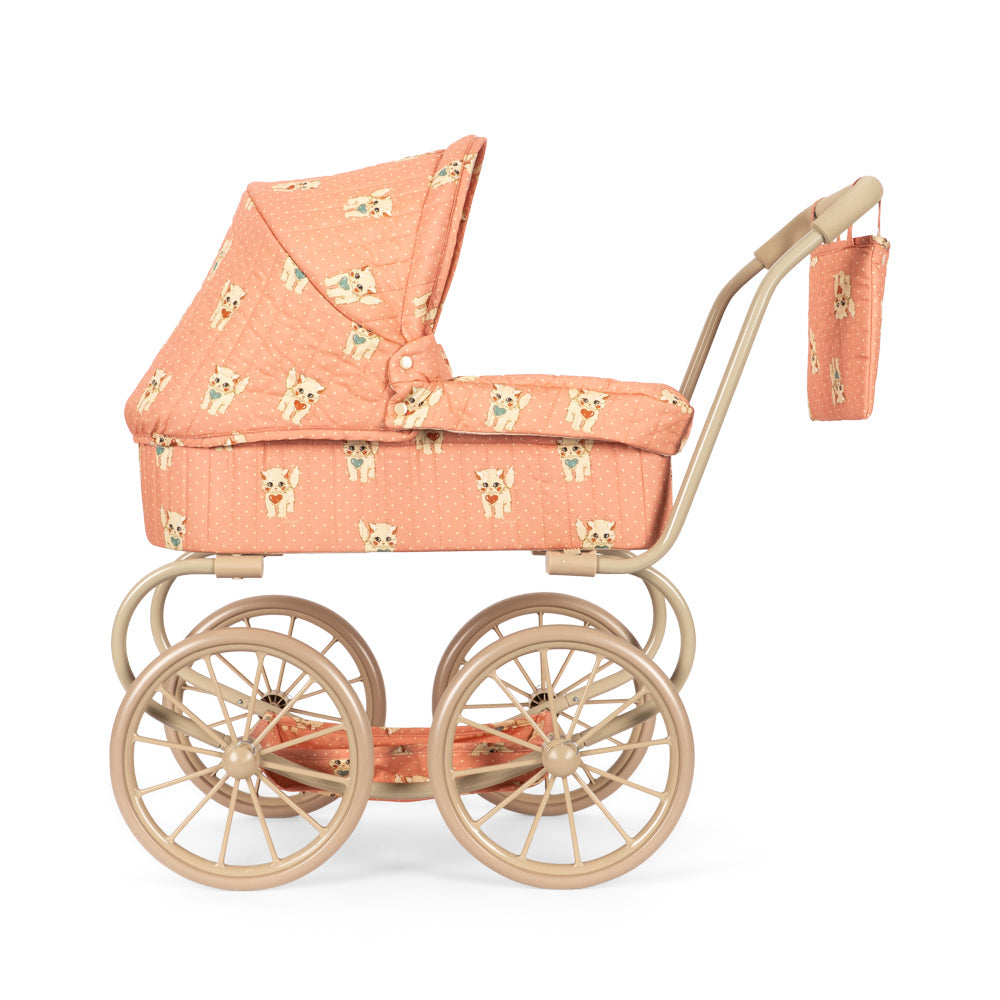 A vintage-style toy or doll pram with a peach fabric cover printed with small dog faces, mounted on a light wood frame with four wheels and a matching handle.