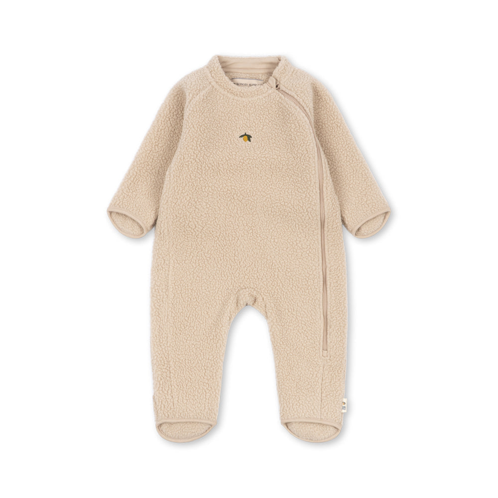 A baby's long-sleeve footed sleeper in a soft, textured beige fleece fabric, featuring a small embroidered animal logo on the left chest, displayed against a solid white background.