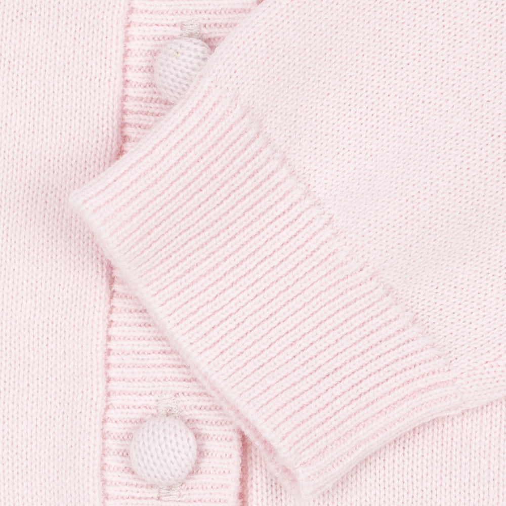 Close-up of a light pink knit cardigan with a ribbed button placket and matching buttons.