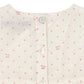 Close-up of a cream-colored dress with pink floral pattern and buttons.