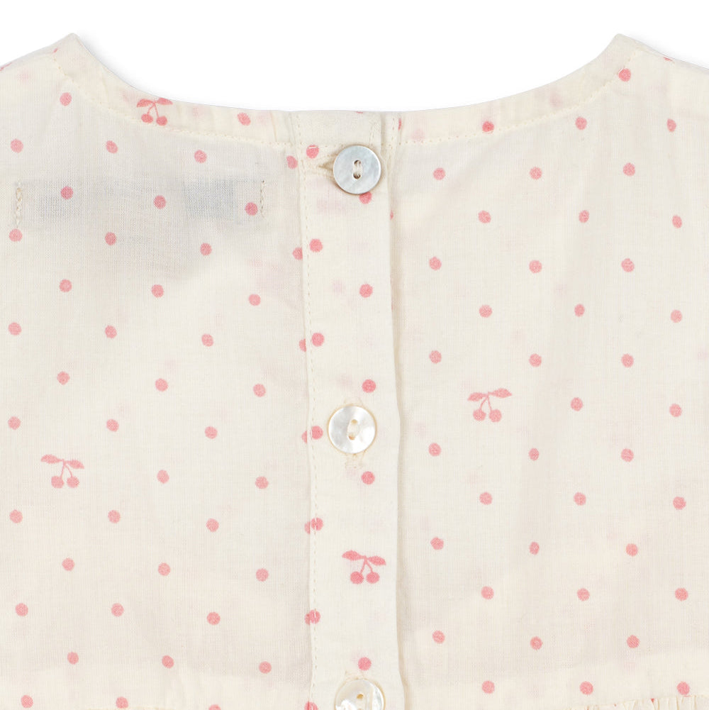 Close-up of a cream-colored dress with pink floral pattern and buttons.