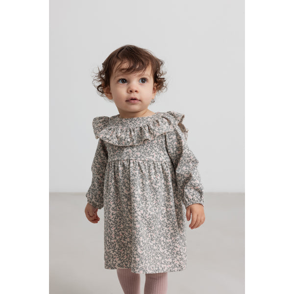Child wearing a floral dress on a plain background