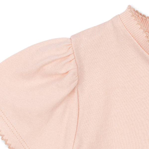 Close-up of a girls light pink blouse with ruffled sleeves on a white background
