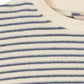 Close-up of a striped knit top with horizontal navy blue stripes on an off-white base, featuring a ribbed cream crew neck.